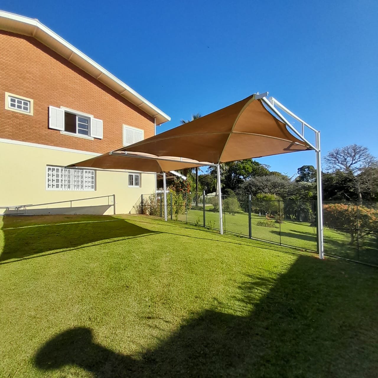 Imagem de toldos e coberturas instalados para proteção solar e conforto em áreas externas.